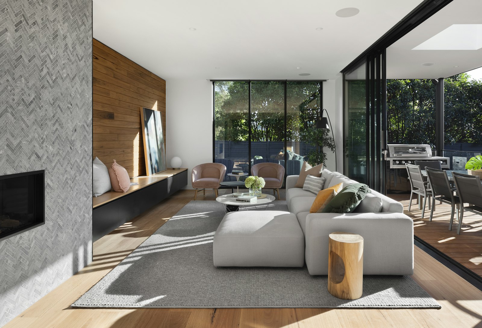 Open living room looking out to a deck and hedges