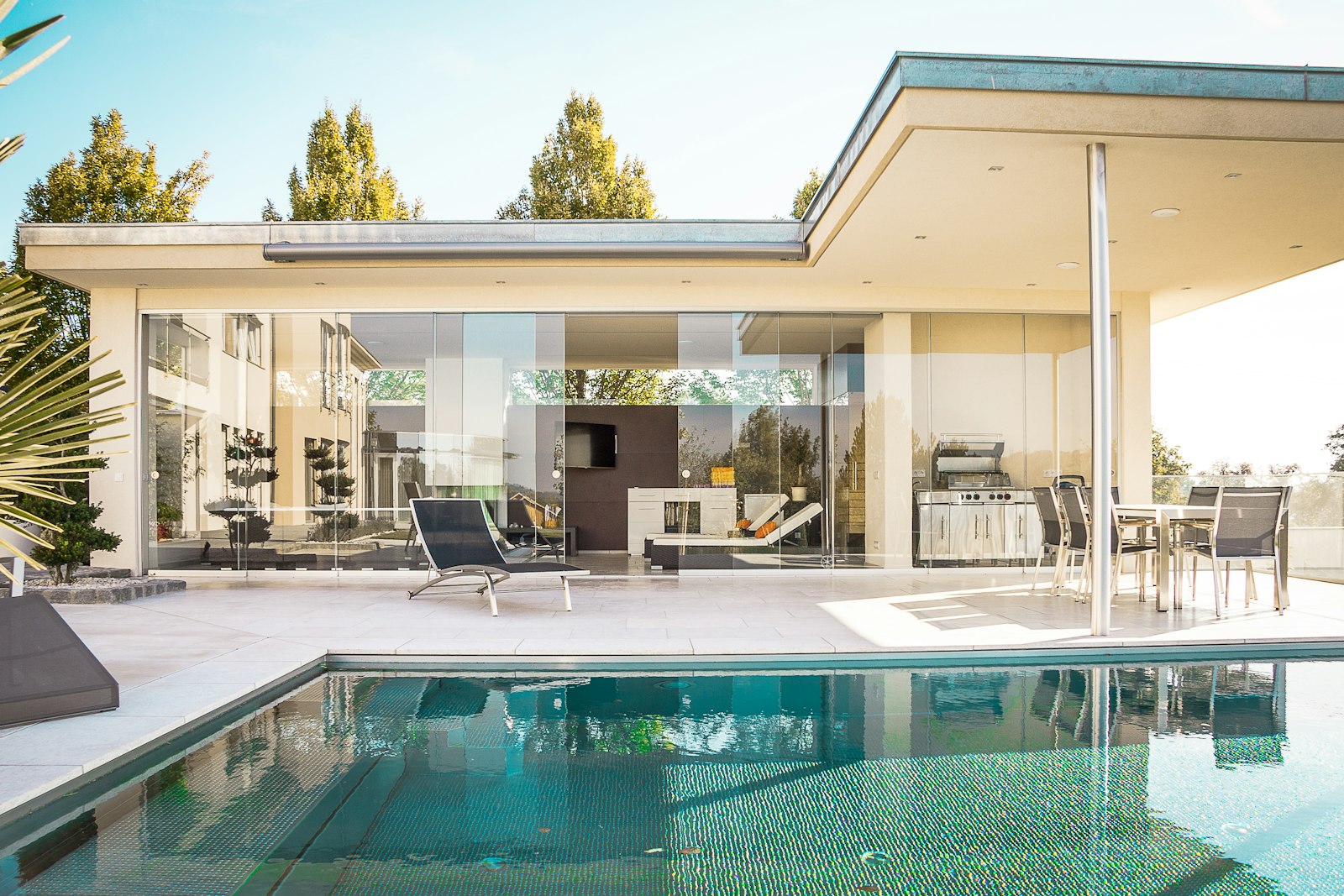 Glass-walled home opening onto a quiet pool deck