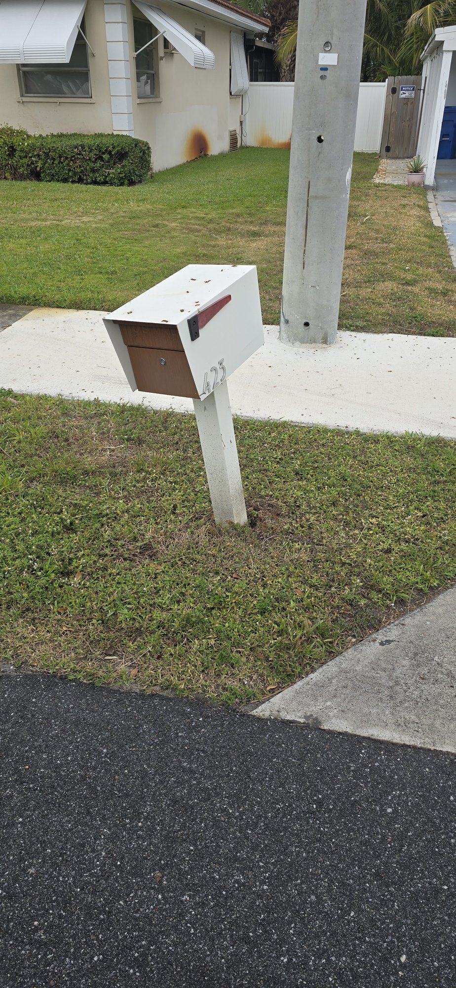 White mailbox on a post by the sidewalk